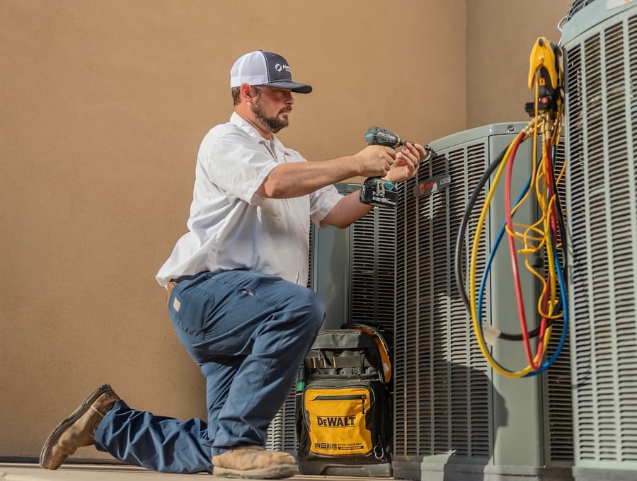HVAC technician conducting AC maintenance on unit.