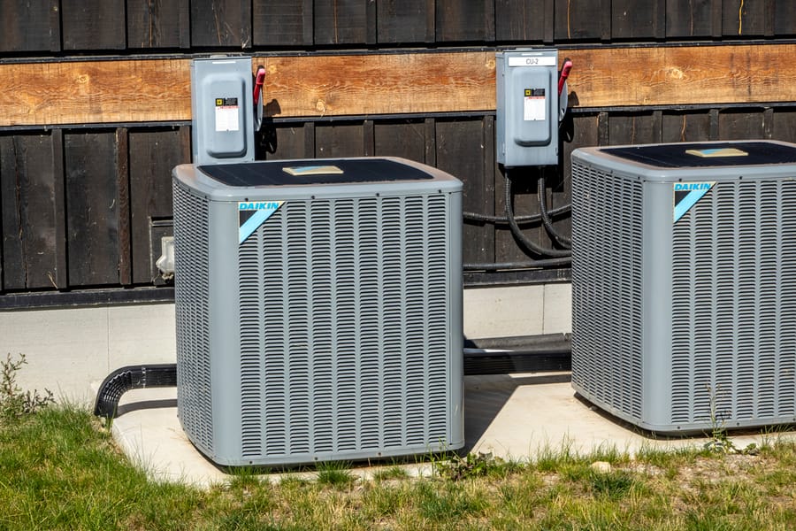 Two AC units outside home in sunny weather.