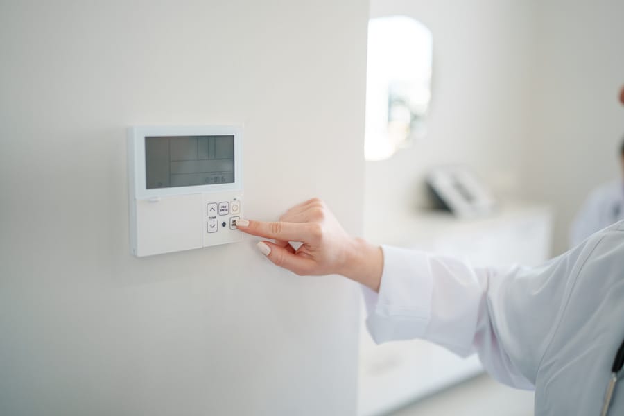 Thermostat on wall being adjusted.