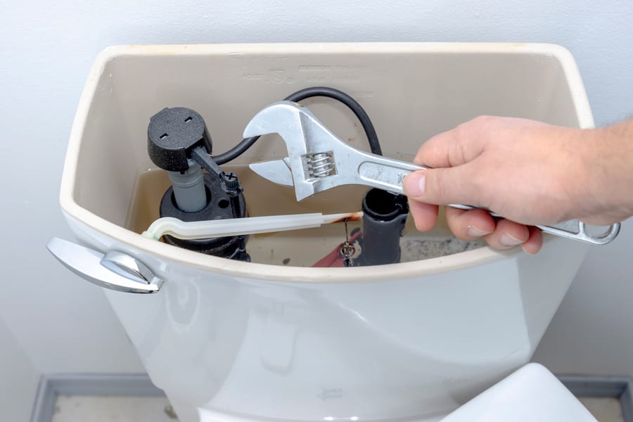 A plumber conducting toilet repairs.