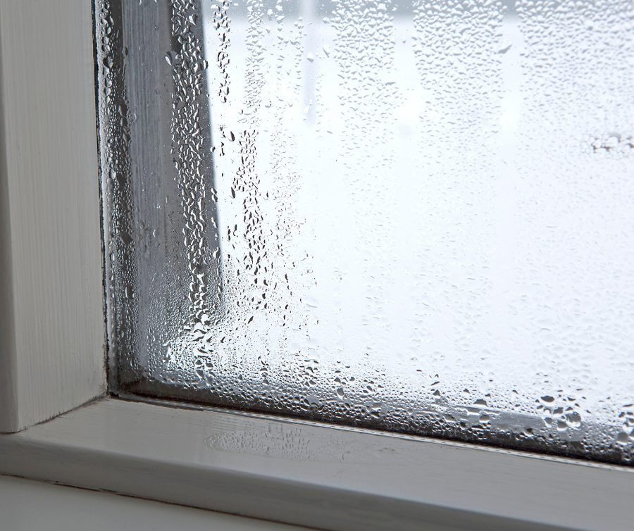 Window inside of a home with condensation on it; indoor humidity concept