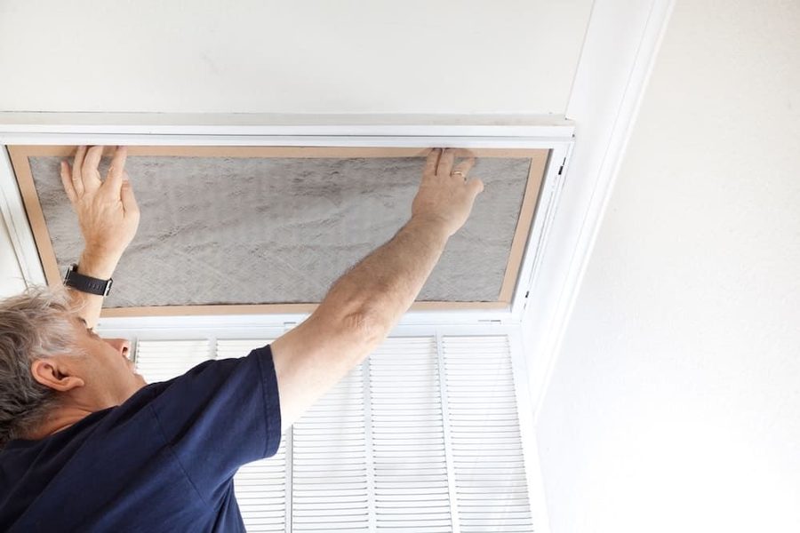 HVAC technician replacing air filter for HVAC system to improve indoor air quality